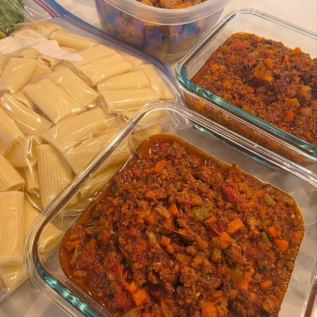 Uncooked rigatoni and a meat sauce packed in separate glass containers.