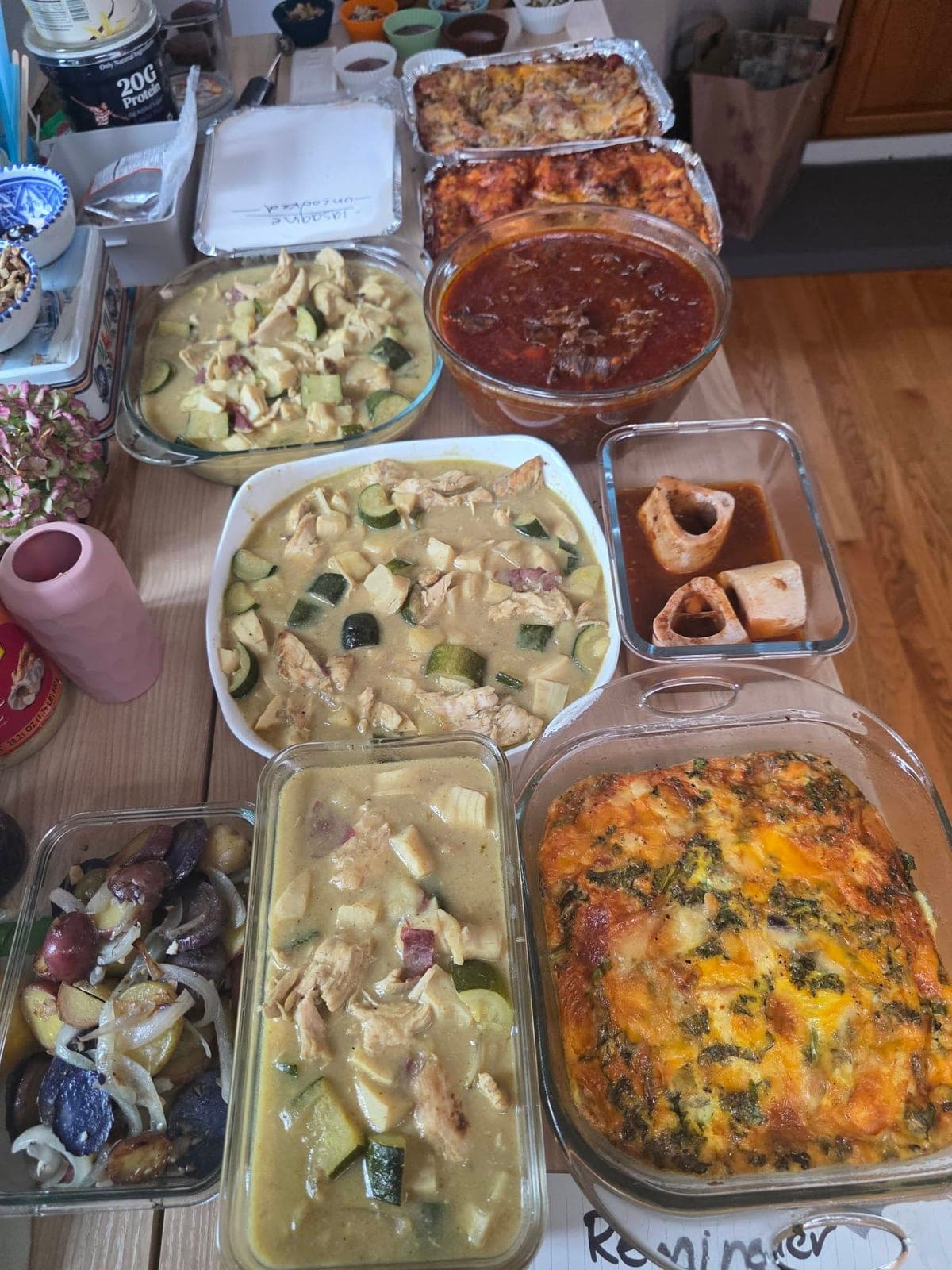 Glass baking dishes on a counter holding lasagna, green chicken curry, a frittata and breakfast potatoes.